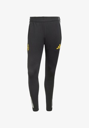 Schwarze Sporthose mit elastischem Bund, mit gelben Logos von Real Madrid und Adidas sowie weißen Streifen an den Seiten.