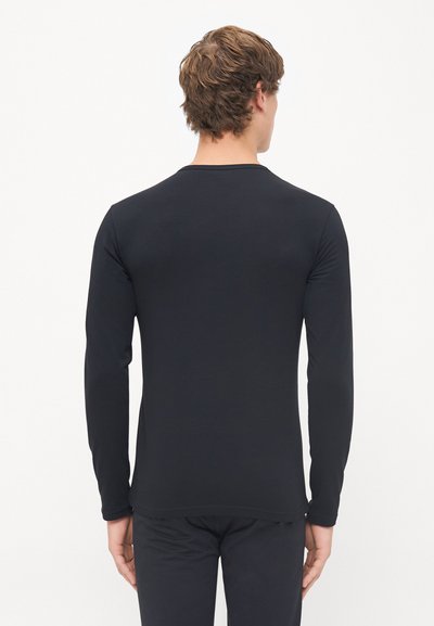 Chemise noire à manches longues en tissu lisse. Dotée d'un col rond et d'une coupe ajustée. Le tissu semble doux et léger.