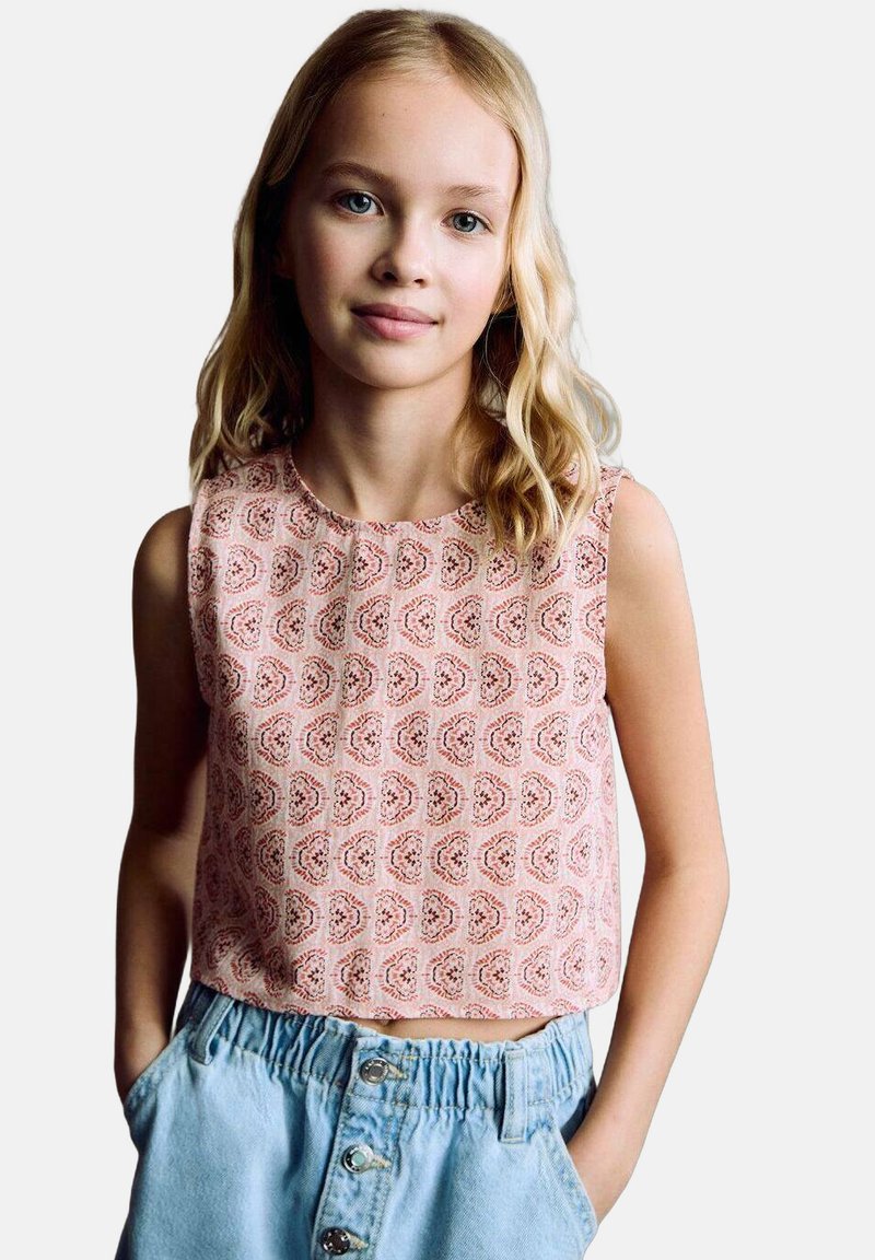 Růžový bezrukávový top se vzorem paisley, spárovaný s světle modrou sukní s knoflíkovým zapínáním a elastickým pasem.