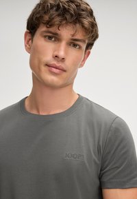 Grijze katoenen t-shirt met korte mouwen, ronde halslijn en geborduurd "JOOP!" logo op de borst. Gladde textuur, getailleerd ontwerp.