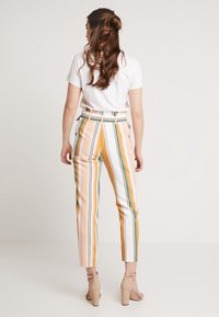 Pantaloni a righe che presentano una miscela di colori pastello tra cui rosa, giallo, verde e bianco, con una vestibilità su misura e lunghezza alla caviglia.