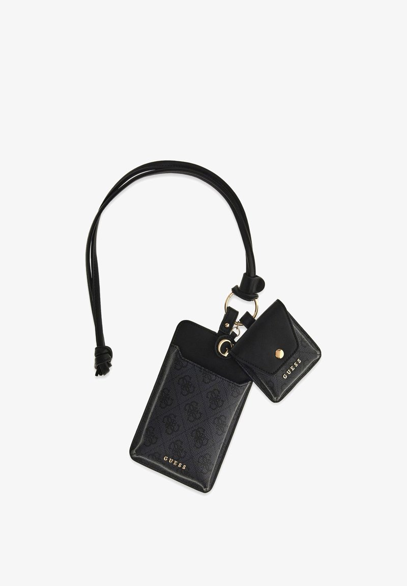 Zwarte Guess polszak met monogrampatroon, bevestigd met een klein muntenportemonneetje met drukknoopsluiting, beide verbonden door een leren lus en gouden ring.
