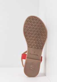 Sandales rouges avec une semelle extérieure en caoutchouc marron texturée, présentant un design simple et des sangles réglables. Taille 37 indiquée sur la semelle intérieure.