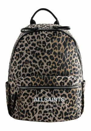 Personne portant un sac à dos AllSaints à imprimé léopard avec une poche avant zippée et des bretelles noires sur un fond clair uni.