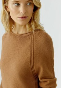 Brauner Strickpullover mit Rundhals, der gerippte Akzente an den Schultern und eine weiche Textur aufweist.