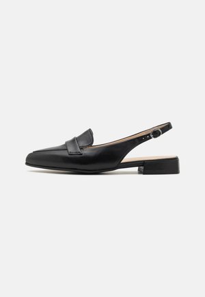 Chaussure slingback en cuir noir avec un talon plat, un bout pointu et une lanière décorative sur le coup de pied. Présente un détail de boucle circulaire.