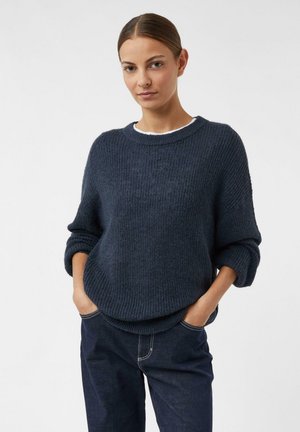 Marineblauer Strickpullover mit rundem Ausschnitt, weitem Ärmel und lockerer Passform. Strukturierter Stoff, kombiniert mit dunklen Jeans.