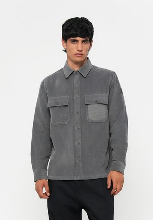 Gray corduroy shirt with long sleeves, button-up front, two chest pockets, and a textured finish. Features a classic collar and relaxed fit.