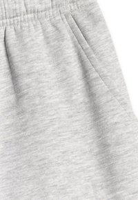 Pantalon en tissu doux gris clair avec une taille élastique et une poche latérale visible sur le côté droit.