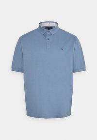 Kortärmad pikétröja i ljusblått bomull. Har en krage med knäppning och en liten logotyp på bröstet.