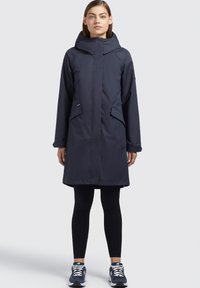 Navy blue, waterproof parka with a high collar, zip closure, and two front pockets. Long sleeves with buttoned cuffs and a relaxed fit.
