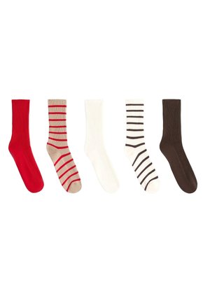 Cinq chaussettes mi-mollet en ligne : rouge uni, beige avec des rayures rouges, blanc uni, blanc avec des rayures noires et brun foncé uni.