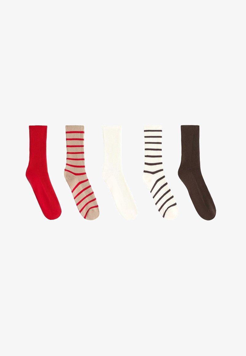 Cinq chaussettes mi-mollet en ligne : rouge uni, beige avec des rayures rouges, blanc uni, blanc avec des rayures noires et brun foncé uni.