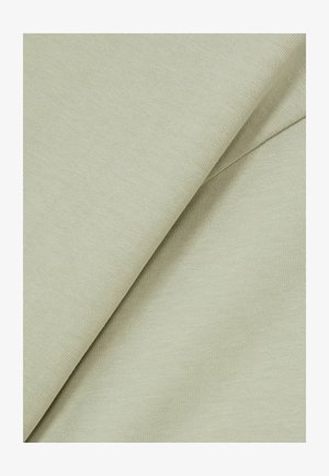 Šviesiai žalia medžiaga su lygiu paviršiumi, turinti subtilų audimo raštą ir du persidengiančius sluoksnius, rodytančius abi puses.