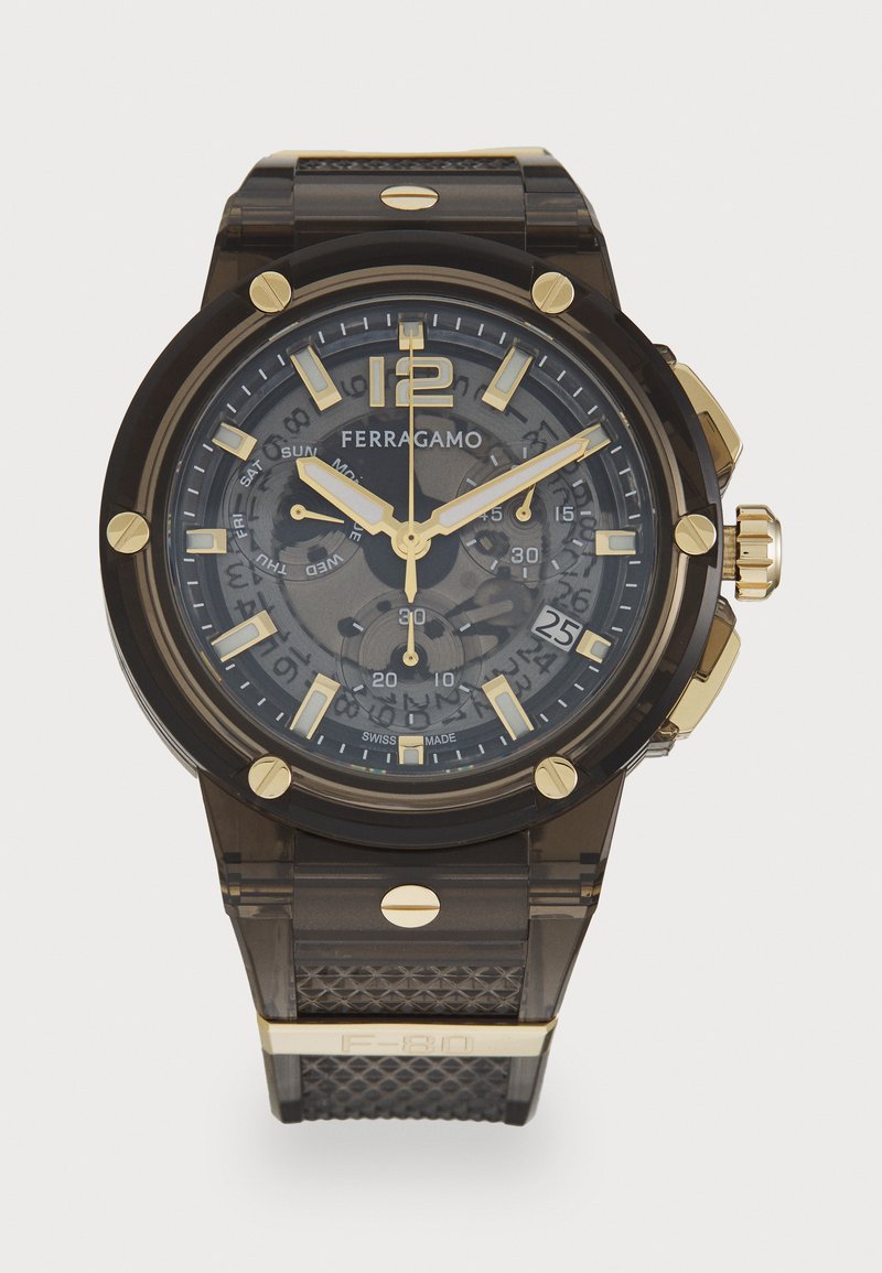 Orologio Ferragamo nero e oro con cassa trasparente, cinturino in gomma testurizzato, display della data e più quadranti per le funzioni di giorno e ora.