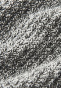 Grau-weißer, gestrickter Stoff mit einem strukturierten Muster, das eine Mischung aus glattem und flauschigem Garn in einem überlappenden Design zeigt.