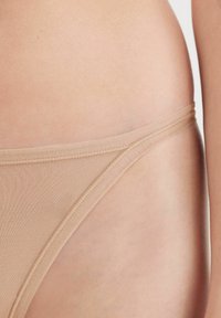 Bikini-ondergoed in een naaktkleur, met een gladde, rekbare stof, dunne tailleband en minimale stikdetails langs de randen.