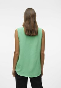 Haut sans manches vert avec une finition texturée, décolleté rond et ourlet légèrement incurvé. Offre une coupe décontractée pour plus de confort.