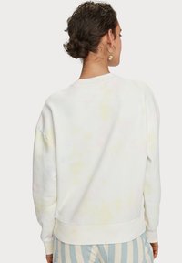 Bluza crewneck w jasnym białym kolorze z pastelowym wzorem tie-dye. Posiada długie rękawy, ściągacze oraz skrócony fason. Miękka struktura.