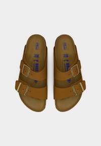 Ζευγάρι καφέ Birkenstock σανδάλια σε ταμπά χρώμα με δύο ρυθμιζόμενες ορείχαλκινες αγκράφες και εργονομικές φετούλες φελλού, μέγεθος 38, από πάνω.