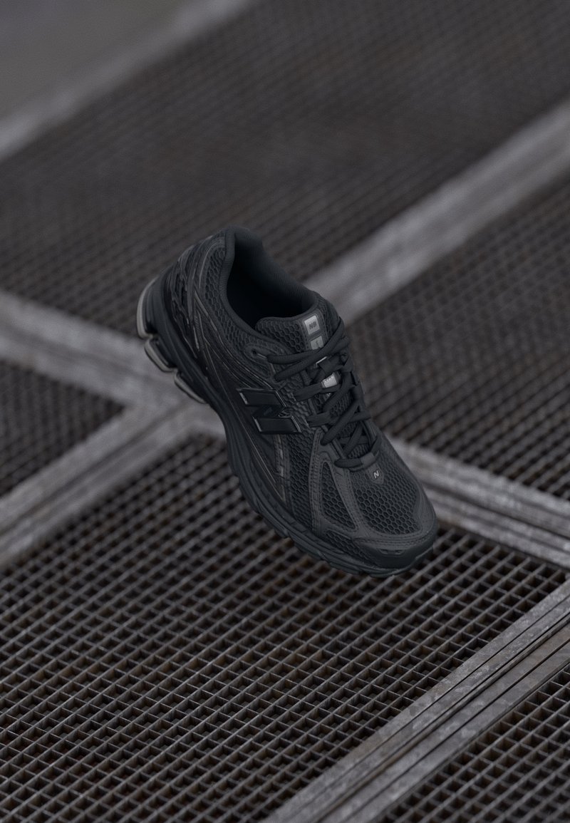 Botte de sport noire avec une tige en mesh, des accents texturés et une semelle rembourrée. Design à lacets et détail de logo sur le côté.