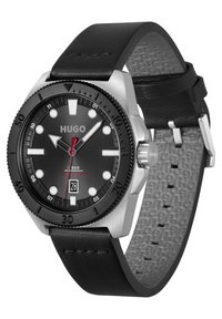 Reloj con correa de cuero negro, esfera negra mate, caja de acero inoxidable plateado, marcadores de hora blancos y una pantalla de fecha a las 6 en punto.