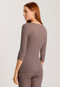 Brown ribbed long-sleeve top with a scoop neckline and lace trim on sleeves. Body-hugging fit, smooth texture, and minimal design.