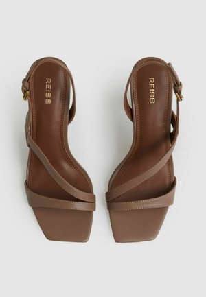 Hnedé kožené sandále na vysokom opätku s otvorenou špičkou a tenkými popruhmi. Špičky v štvorcovom tvare a polstrovaná stielka. Zlatý logomotiv na vnútornej strane.