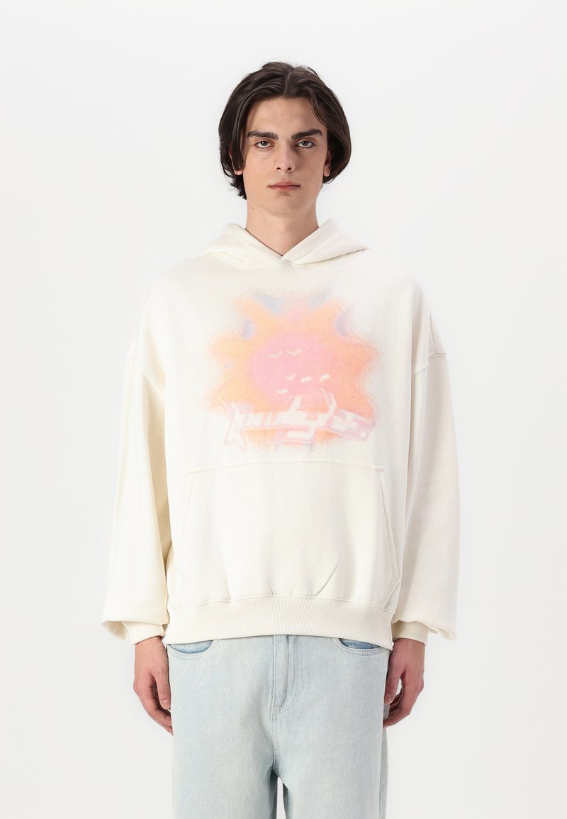 Lys beige oversized hettegenser med et rosa og blått solmotiv på framsiden. Utformet med en frontlomme og snøring på hetten.