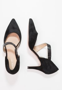 Czarne zamszowe buty na wysokim obcasie z wężowymi noskami, paskiem na pięcie i teksturowanym czarnym paskiem na obcasie. Gładka podszewka wewnętrzna.