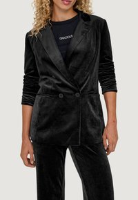 Blazer in velluto nero con design doppiopetto, revers a scollo e tasche frontali. Maniche lunghe con una texture liscia e morbida.