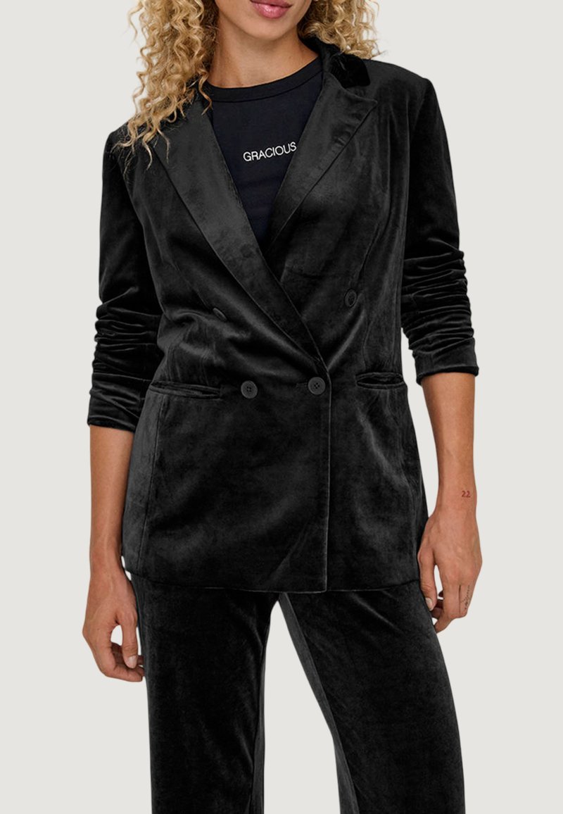 Blazer in velluto nero con design doppiopetto, revers a scollo e tasche frontali. Maniche lunghe con una texture liscia e morbida.