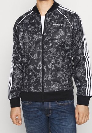 Czarna kurtka na zamek firmy Adidas z białymi trzema paskami na rękawach, z białymi rysunkami konturowymi postaci z kreskówek, które jeżdżą na deskorolce i grają w baseball.