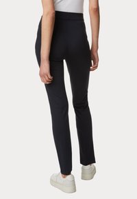 Námořnické přiléhavé kalhoty s vysokým pasem, hladkou texturou a zúženým střihem. Spárovány s bílými teniskami s masivní podrážkou.