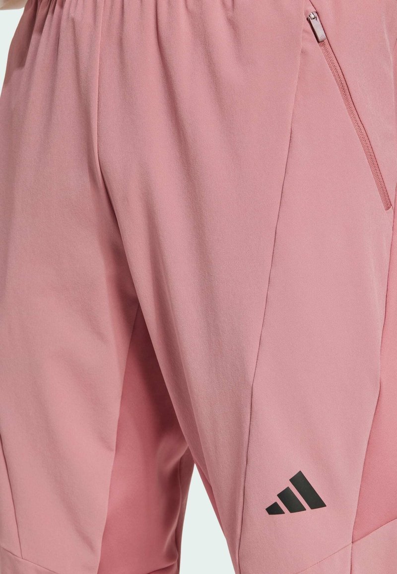Helle pinke Sportshorts aus glattem Material. Verfügt über eine schräg eingesetzte Seitentasche mit Reißverschluss und schwarze Logodetails.