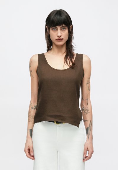 Débardeur en lin marron avec un col dégagé, sans manches et une coupe décontractée, associé à un pantalon de couleur claire. Tissu texturé avec un éclat subtil.