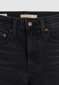 Zwarte denim jeans met een kick bootcut ontwerp, voorzien van een knoopsluiting, riemlussen en minimalistische details op de stof.