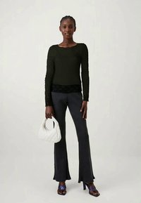 Top preto de manga longa, textura canelada, combinado com calças flare listradas. Acessórios incluídos: uma mala acolchoada branca e sandálias de salto azuis.