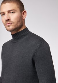Dunkelgrauer Strickpullover mit Rippenrollkragen. Verfügt über eine strukturierte Oberfläche und eine taillierte Silhouette, die ein elegantes Design betont.