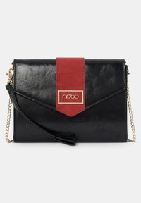 Czarna torebka z ekoskóry z czerwonym zamszowym akcentem, złotym okuciem i odpinanym łańcuszkowym paskiem. Posiada kopertowy fason i detal z logo.