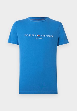 Niebieska bawełniana koszulka z krótkim rękawem, okrągłym dekoltem, z białym logo "TOMMY HILFIGER EST. 1985" na piersi, minimalistyczny design, gładka tekstura.