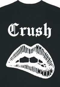 Čierna mikina s bielym gotickým písmom s nápisom "Crush" nad výraznou grafikou otvorených pier s jasne definovanými liniami a tieňovaním.