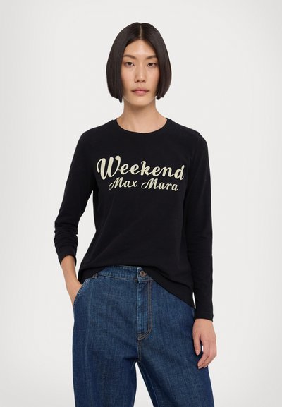 Svart langermet t-skjorte med "Weekend Max Mara" tekst i lysbeige. Kombinert med løstsittende blå denimjeans. Enkelt, avslappet design.