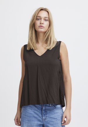 Débardeur marron sans manches avec un col en V, fabriqué à partir d'un tissu doux. Coupe ample avec des détails froncés sur les côtés. Associé à un jean bleu clair.