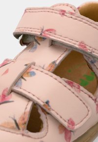 Ροζ δερμάτινο σανδάλι με λουλουδάτο σχέδιο, διπλά λουράκια με βέλκρο, ανοιχτές μύτες, μπεζ πάτος και λείο υλικό.