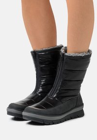 Schwarze wasserdichte Stiefel mit gepolstertem Design, Reißverschluss und grauem Fleece-Futter. Mit einer strukturierten grauen Gummisohle für besseren Halt.