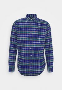 Chemise à carreaux à boutons dans des tons de bleu, vert et blanc. Comprend des manches longues, un col et un ourlet arrondi. Logo Levi’s sur la poche poitrine.