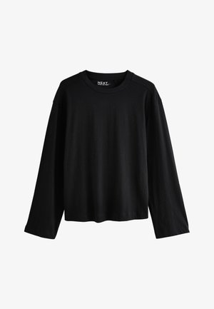 Mustast puuvillast pika säärega klassikalise kaelusega särk, mis on vaba lõikega ja mille sees selja taga kaelas on nähtav kaubamärgi silt.