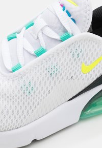 Nike-sneakers med en vit mesh-övre del och turkosa samt rosa accenter, en gul logotyp och en genomskinlig grön luftkudde i sulan.