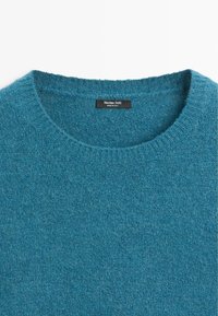 Maglione lavorato a maglia color verde acqua con scollo rotondo. Tessuto morbido e collo a coste. L'etichetta recita "Massimo Dutti", indicando origine italiana.